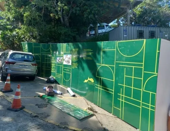 Tapume verde adesivado em grande formato, durante a instalação